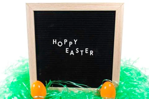 A Sign That Says Happy Easter With Two Orange Easter Eggs and Green Easter Gr Stock Photos