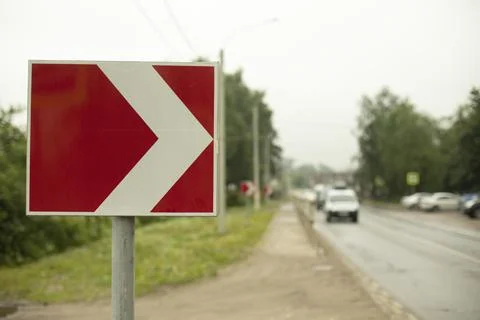 Sign sharp turn. Red road sign. Arrow pointer on road. Stock Photos