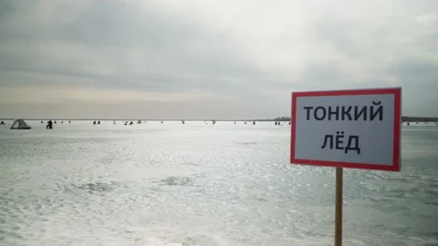 The sign "Thin Ice" prohibits going on the ice. And the fishermen are fishing. Stock Footage 238531143