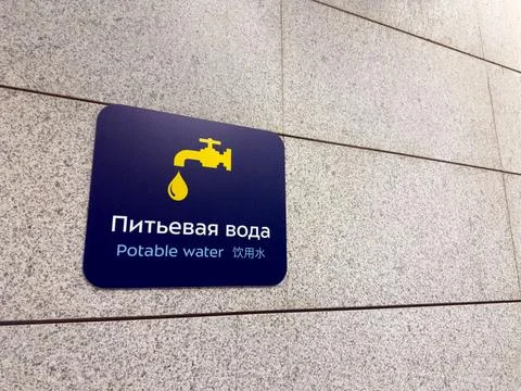 Sign on wall in three languages designating location for drinking fountain... Stock Photos