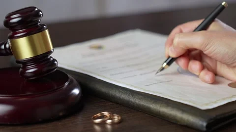 Signing divorce document. Wedding rings and gavel with a woman signing a co.. Stock Footage 287547352