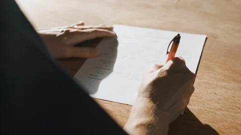Signing an Important Document on a Well-lit Table Stock Footage 128655925