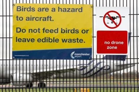 Signs about bird strikes on security fencing at Manchester Airport, UK. Stock Photos