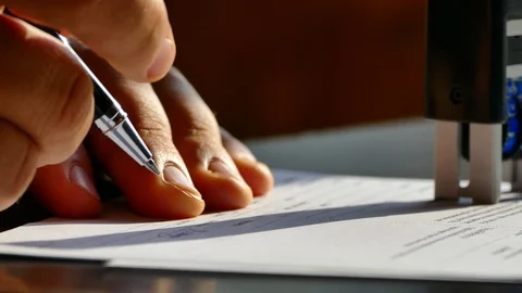Signs the document with a ballpoint pen on the table. Signature of the agreement Stock Footage