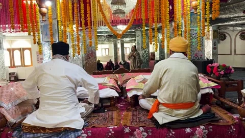Sikh priests reading guru granth sahib inside gurdwara decorated with marigold Stockbeeldmateriaal 334560354