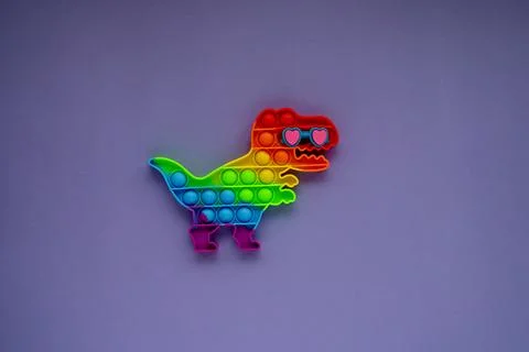 Silcone toy pop it in shape of dinosaur on the purple background. Antistress  Stock Photos