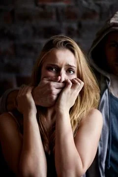 Silenced by fear and force. Abused young woman being silenced by her abuser. Fotos Stock