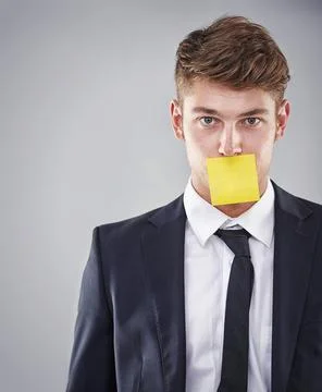 Silenced by work. a business man with a post it note stuck to his mouth. Stock Photos
