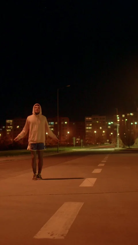 Silent pedestrian moves confidently beneath glowing city lamps Vidéo 333877231