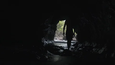 Silhoette Walking in Cave by beach Stock Footage 82049316