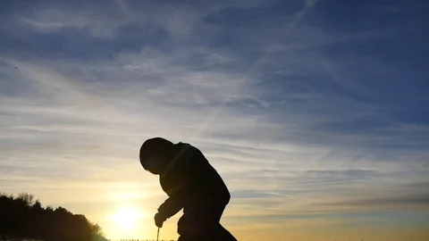 Silhouette of 2 years old boy outdoors looking to the something on the ground Stock Footage 100290314