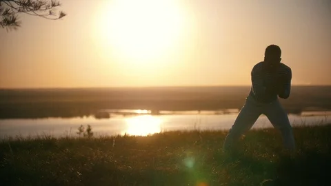 Silhouette of acrobatic man performs martial tricks with dance elements on the Stock Footage 90382227