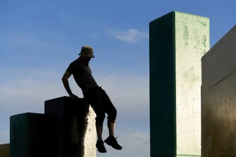 Silhouette of an active man jumping between concrete blocks practicing parkou Foto stock