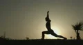 Silhouette of active woman practicing yoga positions, doing exercises at sunset HD Footage