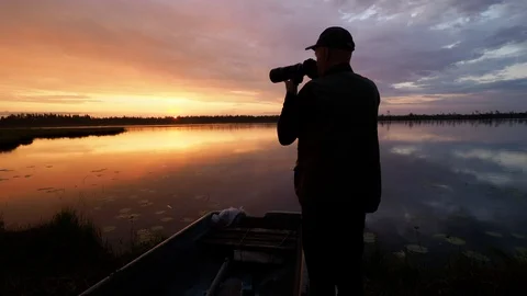 Silhouette of adventure photographer taking pictures at sunrise in Finland Stock Footage