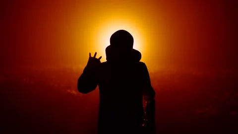 Silhouette of alien waving hand - hello on orange background. Humanoid on Stock Footage 200409871