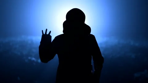 Silhouette of alien waving hand - hello on blue, night background. Humanoid on Stock Footage 200410016