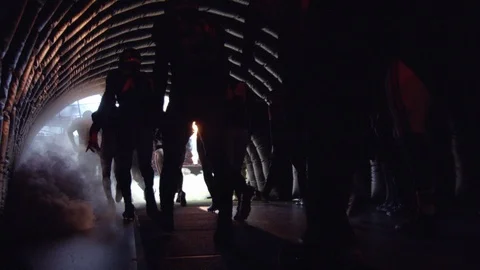 Silhouette of American football players running through tunnel towards field Stock Footage