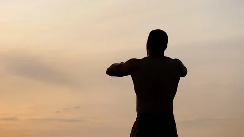 Silhouette of athletic man with a bare torso posing shows his muscles against Stock Footage 115025289
