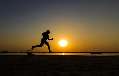 Silhouette of athletic running on the sun rise beach. Stock Photos
