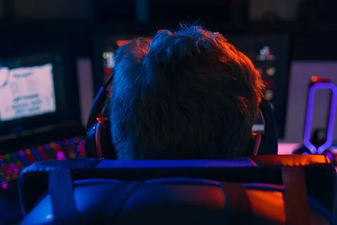 Silhouette of the back of a young man addicted to video games playing on a Stock Photos