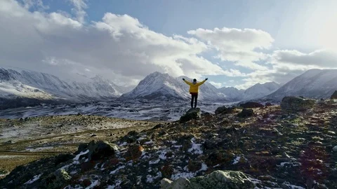 Silhouette of backpacker walking towards the edge of a rocky peak to contemplate Stock Footage 99192600
