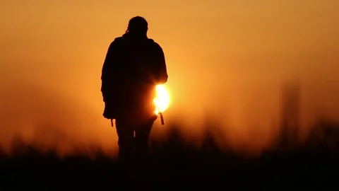 A silhouette of a backpacker walking towards the sun Video stock 165499253
