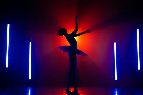 Silhouette of ballerina is practicing elements in studio with neon colorful Stockfoto's