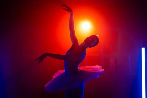 Silhouette of ballerina is practicing elements in studio with neon colorful Stock Photos