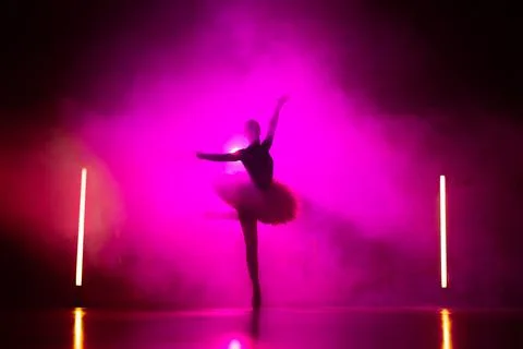 Silhouette of ballerina is practicing elements in studio with neon pink light 写真素材
