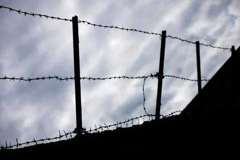 A silhouette of barbed wire against a cloudy sky Stock Photos