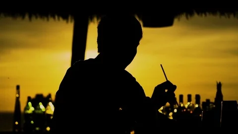 Silhouette of barman preparing cocktail at sunset outside Stock Footage 75002232