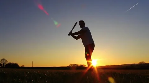 Silhouette of baseball player hitting ball, sunset Stock Footage 48976072