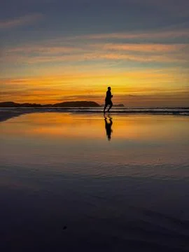 Silhouette of beach runner at sunset Stock Photos
