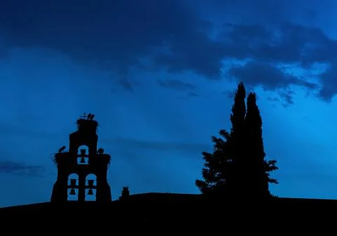 Silhouette of bell tower with storks Stock Photos
