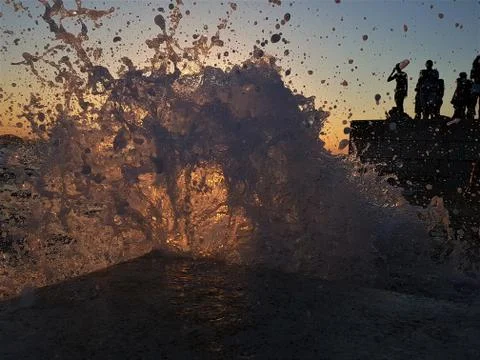 Silhouette of a big wave exploding to the camera with people in the background Foto stock