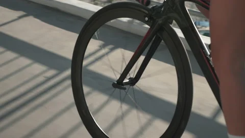 Silhouette of bike wheel in sunset light. Girl is pedaling bike, close up of Stock Footage
