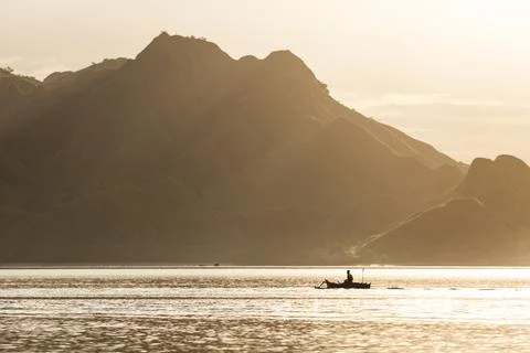 Silhouette of a boatman rowing in the golden sea Stock Photos
