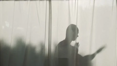 Silhouette of a bold man dancing behind curtains. Contrasting shadow in the Stockbeeldmateriaal 158928527