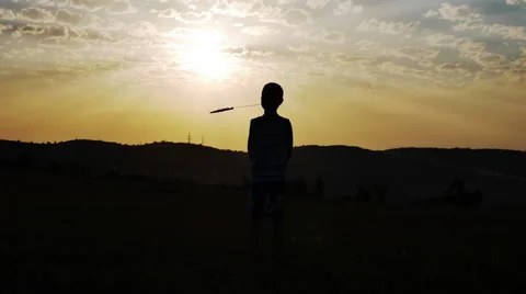 Silhouette of a Boy on the Background of the Sun Keeps in His Mouth a Straw Stock Footage 67330305