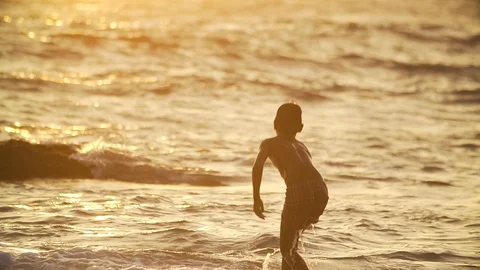 Silhouette of boy bathed in the warm ocean Stock Footage 85622529