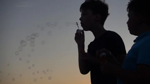 Silhouette Of Boy Blowing Up Soap Bubbles on Sunset Background 스톡 동영상 109703433