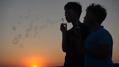 Silhouette Of Boy Blowing Up Soap Bubbles on Sunset Background Stock Footage 109704781