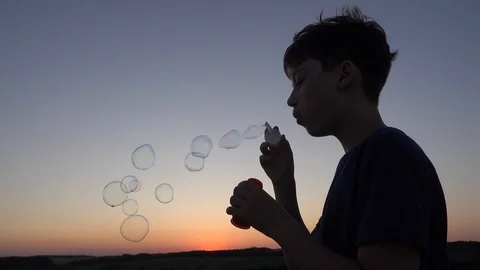 Silhouette Of Boy Blowing Up Soap Bubbles on Sunset Background Stock-Footage 109705637