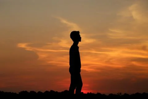 A silhouette of a boy during sunset Stock Photos