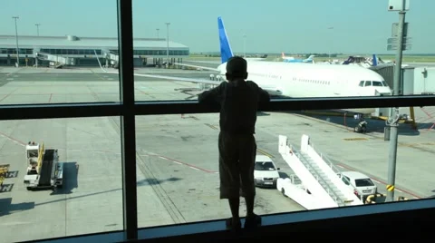 Silhouette of boy looks through window at planes at airport Stock-Footage 6374432