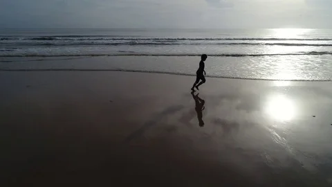 Silhouette boy running at the beach Stock Footage 77583601