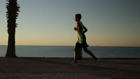 Silhouette of a boy running with a beautiful sunset in the background. Young 스톡 동영상 211091708