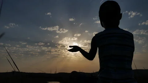 Silhouette of a Boy Sitting on a Background of Sunset Stock Footage 67263021