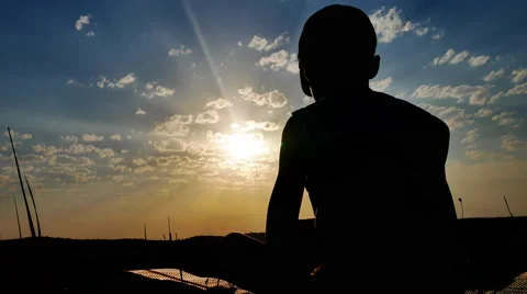 Silhouette of a Boy Sitting on a Background of Sunset Stock Footage 67263057